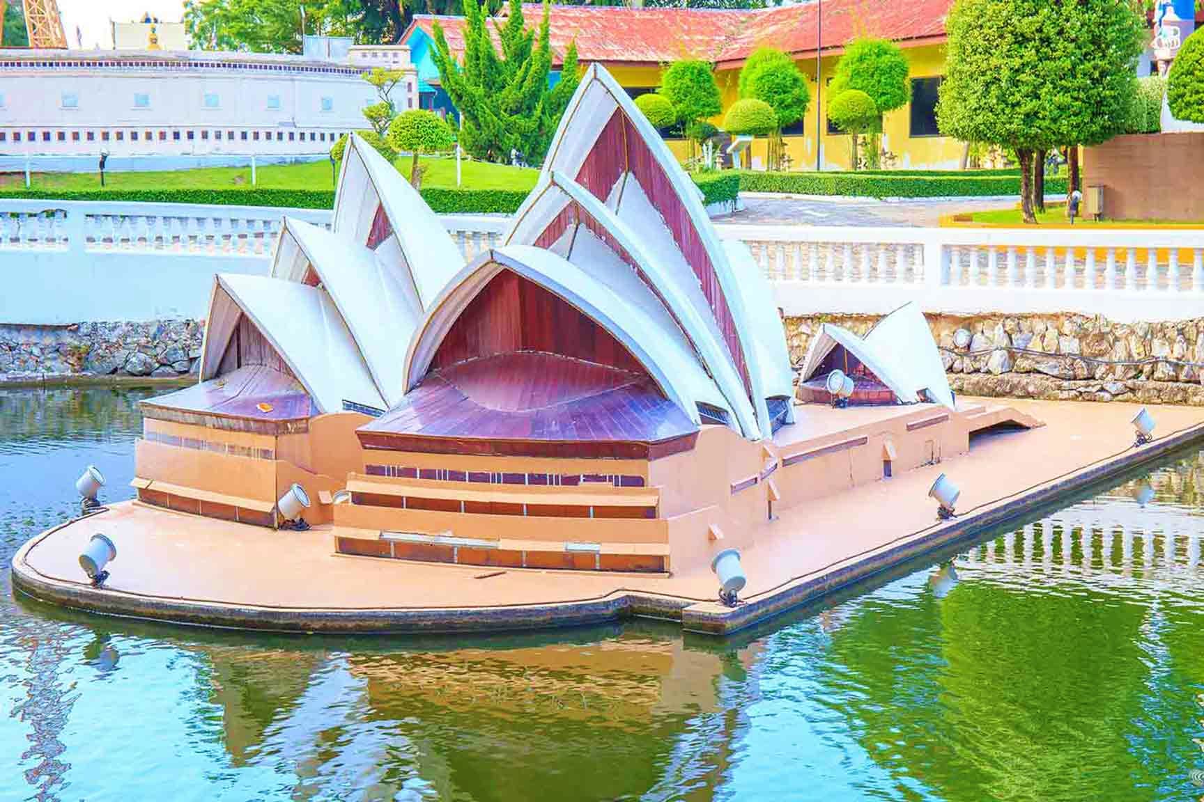 Australia Visa Sydney Opera House replica with distinctive white shell roof sections and burgundy interior, surrounded by water and landscap